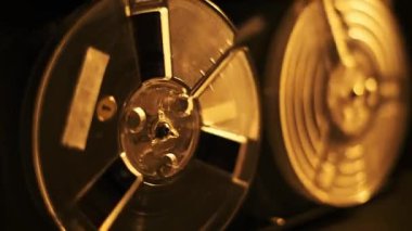 Dönen vintage kasetlerin, dönen hareketlerini vurgulayan bir retro ses oynatıcının altın yakın plan görüntüsü. Analog çağa nostaljik bir bakış açısı kazandırıyor..