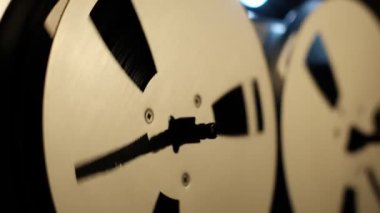 Çalışan bir retro ses kasedini kapat. İki gümüş makaranın karanlık bir arka plana dönmesi klasik, endüstriyel bir his yaratıyor. Dönen metal elementlere odaklan, eski bir çağı yakala