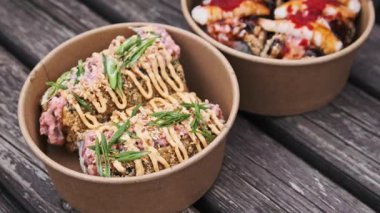 Tahtadaki suşi kaselerinin detaylı yakın plan görüntüleri. Karidesli suşiye tobiko soslu kızarmış rulo sosa ve soğana odaklan. Modern sokak yemekleri dışarıda servis ediliyor..