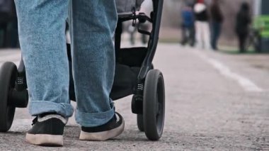 Şehrin arka planında bulanık bir bebek arabasını iten bir kadının bacaklarının düşük kesimli görüntüsü..