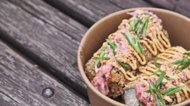 Yavaş çekim tavaları, çıtır çıtır tempura suşileri, bol bol kremalı pembe ve sarı soslar serpiştirilmiş, susam tohumları ve taze yeşil soğanları paket kâğıdına sarılmış..