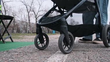 Bebek arabalarının asfalt üzerinde hareket eden, kentsel hareketliliği ve aile gezilerini ön plana çıkaran yakın açılı bebek arabalarının görüntüsü.