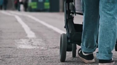 Genç bir kadın, şehir caddesinde bebek arabasıyla gezerken görülüyor..