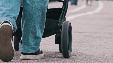 Park yolunda bebek arabasını iten bir kadını arkadan takip etmek gibi. Kamera vücudunun alt kısmını yakalar ve bebek arabaları hareket halindedir. Diğer parka gidenler ve atıştırmalık büfeler