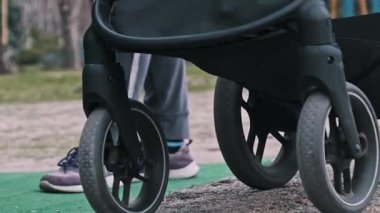 Bir bebek arabasının zemin katındaki manzarası kaldırım ve çimlerin karışık bir yüzeyinde hareket ediyor..