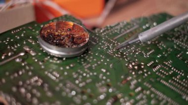 Yakın çekim makro görüntüsü kızgın lehim ucu reçine akışı ile temizlendi, sonra lehimi yeşil baskılı devre kartının bağlantı noktasına eriterek duman yarattı. Onarım süreci ayrıntıları.
