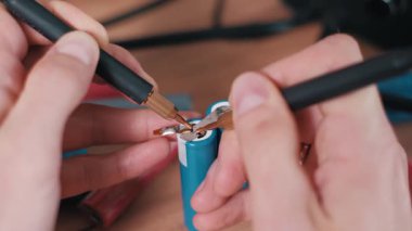 Elektronik atölyesindeki güvenli elektrik montajı için hassas bir alet kullanılarak elle kaynak metal şeridini pil terminallerine yakın çekim.