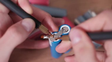 Teknisyenler, enerji sistemleri üretiminde hassasiyet ve güvenliği gösteren özel bir pil paketi için lityum iyon hücreleri arasındaki nikel şeritleri birleştirmek üzere kaynak sondalarını konumlandırıyor.