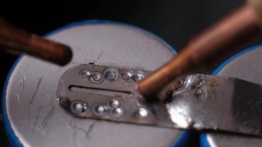 Benek kaynaklamasının makro yavaş çekimde nikel şeridini elektrik bağlantısı sırasında kıvılcımlar saçan iki lityum iyon piline birleştirmesi.