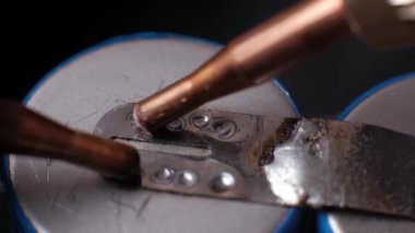 Makro yavaş çekim görüntüleri bakır elektrotların bir pil hücre sekmesinde sıralı kaynak noktaları oluşturduğunu ve parlak kıvılcımların direnç kaynaklama sürecini vurguladığını gösteriyor..