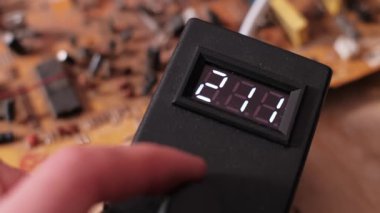 El elektronik bir cihazın kontrol düğmesini ayarlar ve dijital LED ekrandaki numaraların azalmasına neden olur. Voltajın ya da güç ayarlarının azaltılmasının yakın görüntüsü.