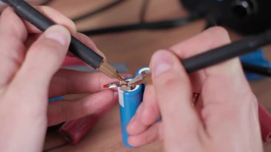 Yakın çekim makrosu mavi 18650 lityum iyonlu batarya terminallerine kaynak nikel şeritlerini bir atölyede hassasiyet ve enerji transferini gösteren DIY pil montajında gösterir.