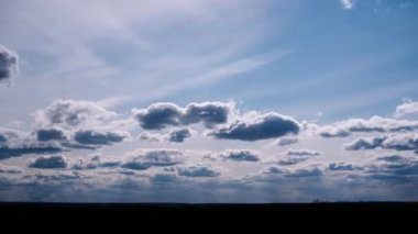 Zaman çizelgesi, bulutların mavi ve beyaz gökyüzünde sürüklendiğini gösteriyor. Hafif güneş ışığı değişimleri, aşağıdaki karanlık ufuk çizgisinde ruh halini değiştiriyor..