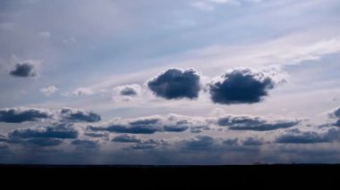 Zaman çizelgesi, gökyüzünü silip süpüren gri ve beyaz bulutları yakalıyor. Değişen ışık, karanlık bir manzaranın üzerinde dengesiz bir etki yaratıyor..