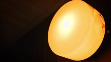 Makro yakın plan görüntüsü, ılık, yumuşak turuncu bir parıltı yayan yuvarlak bir lamba armatürüne odaklanıyor. Donmuş kapak yüzeyi ve koyu ortam arkaplanı ayrıntıları bu iç ışıklandırma çekiminde görülebilir.