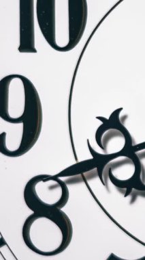 Dikey yakın çekim zaman çizelgesi, beyaz saat yüzünde 8-10 rakamlarını hızla geçen, amansız zaman geçişini sembolize eden süslü elleri gösteriyor..