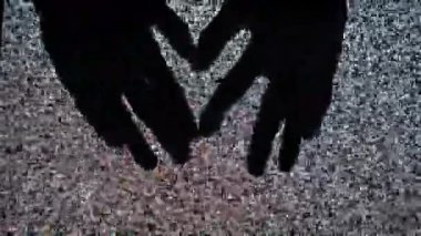 Silüet eller, titreyen televizyon parazitinin arka planına karşı bir kalp şekli jesti oluşturur. Dijital kaosun ortasındaki aşkı ya da iletişimi ya da ekrandaki paraziti simgeler.