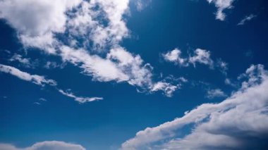 Zaman çizelgesi kümülüs ve ince sirrus gibi parlak mavi bir gökyüzünde sürüklenen ve evrimleşen çeşitli beyaz bulut türlerini ortaya çıkarır. Güneş ışığı dinamik atmosfer sahnesini aydınlatır.