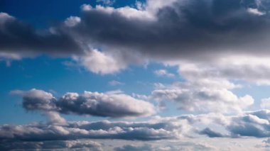 Zaman çizelgesi, canlı mavi gökyüzünde sürüklenen beyaz ve gri bulut oluşumlarını yakalar, oluşumlar dağıldıkça ve yer değiştirdikçe daha fazla aydınlık alanı ortaya çıkarır, dinamik bir hava sahnesi oluşturur..