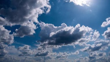 Manzaralı zaman dilimi, üzerimizdeki atmosferin durağan ama sürekli değişen doğasını gösteren, güneş ışınlarıyla aydınlatılan, parlak mavi gökyüzünde huzur içinde yüzen çeşitli bulut oluşumlarını ortaya koyuyor..