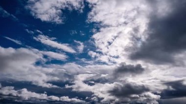 Zaman ayarlı güneş, derin mavi gökyüzünde ilerleyen dramatik beyaz ve gri bulutlar tarafından kısmen gizleniyor. Değişen katmanlar dinamik ışık ve gölge etkileşimi yaratır. Bulutlu ve kasvetli bir atmosfere dönüşür.