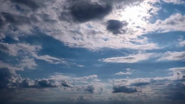 Zaman çizelgesi, güneşin koyu ve beyaz bulutları yararak mavi gökyüzünde dinamik ışık huzmeleri oluşturduğunu gösteriyor. Atmosferik değişiklikler, zaman içinde değişen, hareketli bir gökyüzü ortaya çıkarıyor..