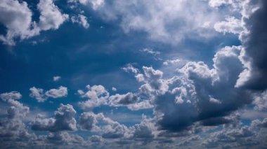 Zaman çizelgesi, canlı mavi gökyüzünde sürüklenen güneş kümülüs bulutlarının dinamik hareketlerini yakalar. Beyaz kabarcıklar üzerinde parlak gölgeler ve ışık desenleri oluşturur..