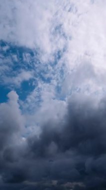 Dikey zaman çizelgesi, mavi gökyüzünde hızla hareket eden koyu ve beyaz bulutların değişen ışık ve gölgelerle dinamik ve değişken bir atmosfer sahnesi yarattığını gösteriyor..