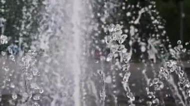 Süper yavaş çekimde çekilen makro çekimlerde havada asılı duran bir fıskiye jetinden ayrı ayrı su damlacıkları görülüyor. Arka planda güçlü, bulanık bir akış var, canlandırıcı, soyut bir sahne yaratıyor..