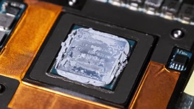 Bir dizüstü bilgisayarın grafiksel işlemci ünitesine eski, kuru termal macunu uygulanmış, bilgisayar bakımı veya onarımı sırasında temizlik ve yenilemeye hazır aşırı yakın çekim görüntüsü.