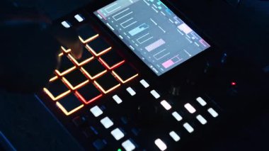 Bir müzik yapımcısının yakın plan görüntüleri canlı, parlayan pedlere basar ve dijital Beatmaker etkileşimli dokunmatik ekran üzerindeki parametreleri tam olarak ayarlar.