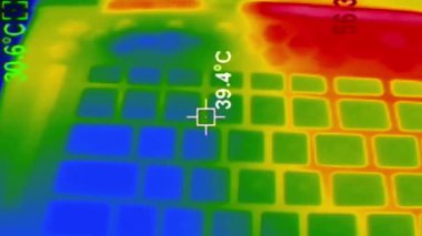 Bir dizüstü bilgisayardaki ısı dağılımını gösteren termal bir kamerayla yakın plan. Sıcaklık dalgalanır, kırmızı ve sarı noktalardaki elektronik sıcak noktaları vurgular, serin alanlar ise mavi kalır.