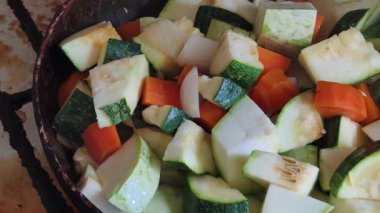 Çiğ, doğranmış sebzelerin canlı bir karışımının aşırı yakın plan görüntüsü. Taze kabak, havuç ve soğanlar bir tavada görülebilir. Yemek pişirmeye başlamadan önce dokularını ve renklerini vurgularlar..