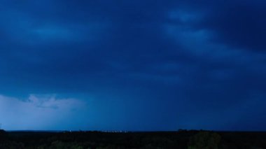 Bir gece vakti, gökyüzünde çalkalanan güçlü mavi fırtına bulutlarını yakalar. Parlak iç şimşekler, uzak, karanlık bir ufuk çizgisinin üzerindeki dokusunu ortaya çıkarır..