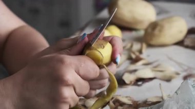 Taze patatesi dikkatlice soyarken kadın elinin makro çekimi. Deri uzun ve sürekli bir spiral halinde çıkar. Sebzeleri pişirme işlemini detaylı bir şekilde gösterir..