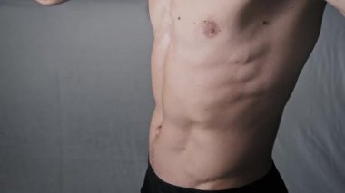 Mide vakumu pozu veren atletik bir adamın yakın çekimi. Derin kas kontrolü, tanımlanmış karın kasları ve zindelik konsepti için göğüs kafesini içine çeker ve içine çeker..