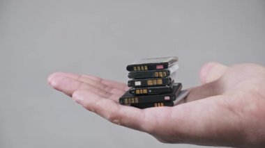 Bir adam açık avuç içi, büyüyen elektronik atık sorununu ve düzgün imha ve geri dönüşüm çözümlerine duyulan ihtiyacı sembolize eden bir yığın eski lityum iyon pili sunar..