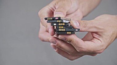 Yakın plan el kameraları, cep telefonlarından kullanılmış lityum iyon pillerini tutuyor. Bu kavram, gri arkaplana karşı e-atık, geri dönüşüm ve tehlikeli madde imhası vurguluyor.