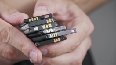 Cep telefonlarından alınmış eski lityum iyonlu pilleri tutan ellerin yakın plan fotoğrafı. E-atık, elektronik bileşen geri dönüşümü ve tehlikeli madde imhası kavramı.