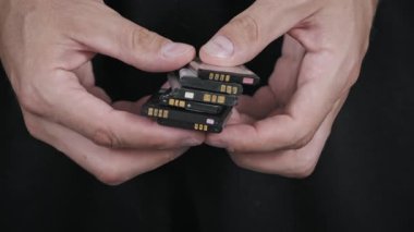 Eski, kullanılmış lityum iyonlu pilleri cep telefonlarından ayıran ve el ele tutuşan kişilerin yakın çekimleri, e-atık kavramını ve akünün geri dönüşüm ihtiyacını vurguluyor.