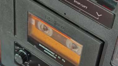 Elle açılan destenin yakın çekimi ve retro teypten eskimiş sarı etiketi, iç mekanizmayı ve siyah plastik kutunun üzerindeki metni gösteren, 80 'lerin nostaljisini çağrıştıran klasik ses kasedini fırlatma..