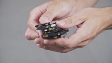 Eski, kullanılmış lityum iyonlu cep telefonu pilleri, e-atık yönetimi ve tehlikeli maddelerin geri dönüşümünü sıralayan erkek ellerinin yakın çekimi.