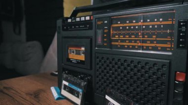 Portakal rengi radyo kadranlı klasik tasarımı ve 80 'lerin kültürünü, retro medyasını ve müzik dinlemesini temsil eden ekstra kasetleri gösteren orta büyüklükte bir müzik kaseti..