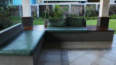 Rahatlamak için yeşil kanepe ve yastıklı açık hava salonu.