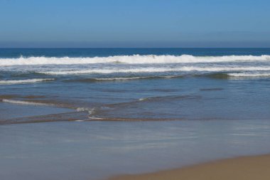 Sakin deniz dalgaları ve açık gökyüzü sahili