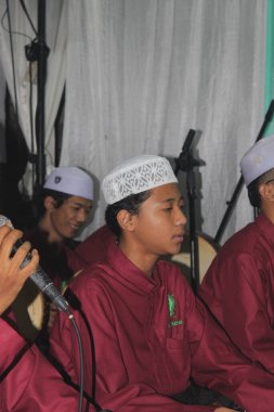 Jakarta, Endonezya - 12 26 2021: Peygamber Muhammed 'in doğum gününü kutlayan kırmızı gömlekli Müslüman bir adamın ifadesi