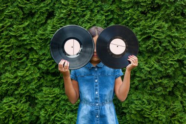 Yazın bir parkta, yeşil ağaçların arka planında plakların plaklarını tutan bir kız çocuğu..