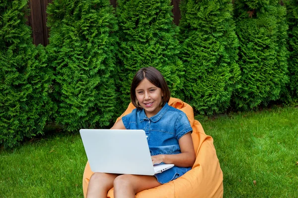 Dziewczynka Siedzi Poduszce Otwartym Laptopem Zielonej Trawie Dziedzińcu Domu Ręce — Zdjęcie stockowe