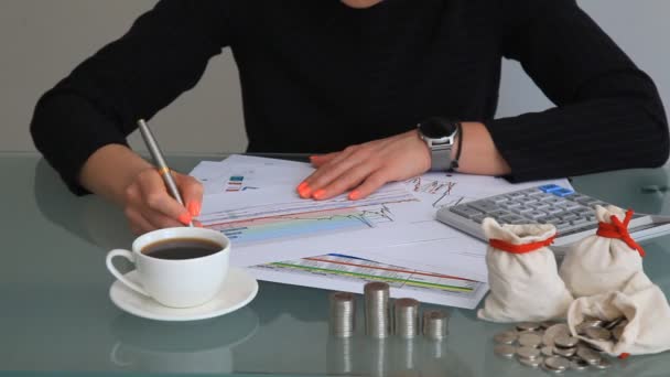 女の子は テーブルに座って コーヒー コンキュレーター コインのカップで 彼女の手にチャートでシートを保持しています ビジネスと金融の概念 — ストック動画