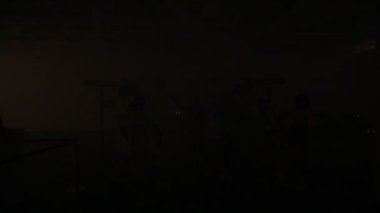 Fenerlerin parlak ışığında bir gece kulübünde dans eden insanların siluetleri.